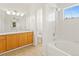 Bright bathroom with a soaking tub, white tiled shower, and a wooden vanity and drawers at 10784 W 63Rd Pl # 205, Arvada, CO 80004