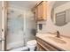 Functional bathroom with a glass-enclosed shower, wooden vanity, and a round mirror, for everyday convenience at 10510 W Fair Ave # A, Littleton, CO 80127