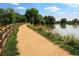 Picturesque walking path with a wooden fence next to a tranquil lake at 4565 Pussywillow Ct, Boulder, CO 80301