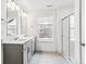 Well-lit bathroom with double vanity, modern fixtures, and a glass-enclosed shower with tiled walls at 13465 Valentia Pl, Thornton, CO 80602