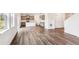 Open-concept living room with wood floors, large windows and modern kitchen at 13465 Valentia Pl, Thornton, CO 80602