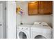 Bright laundry room with a washer, dryer, cabinet, and shelf for laundry supplies at 7840 Ogden Ct, Denver, CO 80229
