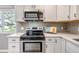 Kitchen featuring modern appliances, white cabinets and backsplash, and quartz countertops at 3354 S Flower St # 52, Lakewood, CO 80227