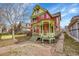 Charming two-story home with a red and yellow exterior with a covered porch and a fenced-in front yard at 3424 N Marion St, Denver, CO 80205