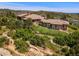 Aerial view of property featuring lush green grass, mature trees and mountain views at 15175 W Belleview Ave, Morrison, CO 80465