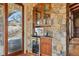 Stylish bar area featuring stone accents, wine storage, custom cabinets, and beverage cooler; perfect for entertaining at 15175 W Belleview Ave, Morrison, CO 80465