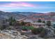 Panoramic view of home nestled in foothills, boasting natural stone and tile roof against the colors of the mountain sunset at 15175 W Belleview Ave, Morrison, CO 80465