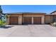 Exterior view of a three-car garage with wooden doors and well-maintained landscaping, offering ample parking space at 15175 W Belleview Ave, Morrison, CO 80465