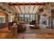 Inviting living room with stone accent walls, wooden beamed ceiling, and large windows framing mountain views at 15175 W Belleview Ave, Morrison, CO 80465