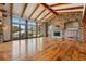 Bright, expansive living area with wood floors, stone fireplace, beamed ceilings, and doors to outdoor scenery at 15175 W Belleview Ave, Morrison, CO 80465
