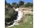 Scenic view of a natural waterfall cascading down rocks surrounded by lush greenery, creating a tranquil setting at 15175 W Belleview Ave, Morrison, CO 80465
