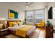 Cozy bedroom with a large window, stylish decor, hardwood floors, and a comfortable bed with yellow accents at 2680 Blake St # 4, Denver, CO 80205