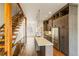 Modern kitchen with island seating, stainless appliances, and adjacent open staircase at 2680 Blake St # 4, Denver, CO 80205