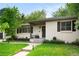 Inviting white brick home with dark shutters, a well manicured lawn, and mature trees at 801 S Harrison St, Denver, CO 80209