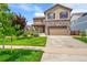 Two story home featuring a stone facade and manicured lawn at 7465 E 157Th Pl, Thornton, CO 80602
