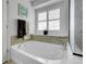 A serene soaking tub with a view to the outside, a rainfall shower head, and travertine surround at 9868 Olathe St, Commerce City, CO 80022