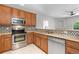 Close up of the kitchen featuring stainless steel appliances, wooden cabinets and a mosaic backsplash at 23456 E 5Th Pl # 104, Aurora, CO 80018