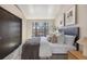Bedroom with a large window offers views of the neighborhood, neutral walls, and modern art at 345 Fillmore St # 409, Denver, CO 80206