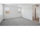 Bright bedroom featuring gray carpeting, two windows, and a doorway to an adjacent bathroom at 2668 Simpson Ln, Erie, CO 80026