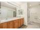 Bright bathroom featuring double vanity, large mirror, and a glass-enclosed shower at 7683 S Biloxi Way, Aurora, CO 80016