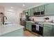 Well-lit kitchen featuring stainless steel appliances, green cabinets, and a practical layout at 7683 S Biloxi Way, Aurora, CO 80016