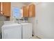 Practical laundry room with white appliances, upper cabinets, and a convenient side-access door at 7683 S Biloxi Way, Aurora, CO 80016
