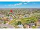 Expansive aerial view of a neighborhood with mature trees, green spaces, and a home marked by a red arrow at 11963 Dahlia Dr, Thornton, CO 80233