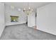 Spacious living room with tall ceilings, plush gray carpet, and a chandelier for ambient lighting at 11963 Dahlia Dr, Thornton, CO 80233