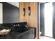 Elegant powder room featuring a sleek black marble vanity, modern lighting, and wood paneling at 580 S Franklin St, Denver, CO 80209