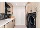 Bright laundry room with modern cabinetry, stylish wallpaper, and a high-end, front-load washer and dryer at 580 S Franklin St, Denver, CO 80209