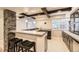 Stylish basement bar featuring a stone accent wall, dark wood beams, and seating at 5660 E Burlington Dr, Castle Rock, CO 80104