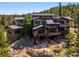 Exterior features multi-tiered decks and stone patio with fire pit, surrounded by lush trees and rocky landscape at 3395 Timbergate Trl, Evergreen, CO 80439