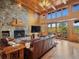 Spacious living room with stone fireplace, wood beams, high ceilings, and sliding doors with scenic views at 3395 Timbergate Trl, Evergreen, CO 80439