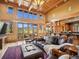 Inviting living room with beamed ceilings, large windows with views, and seamless transition to the kitchen area at 3395 Timbergate Trl, Evergreen, CO 80439