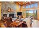 Elegant living room with a stone fireplace, wood ceilings, and scenic mountain views through large windows at 3395 Timbergate Trl, Evergreen, CO 80439