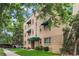 Well-maintained brick apartment building featuring green awnings, manicured landscaping, and mature trees at 2100 N Franklin St # 5, Denver, CO 80205