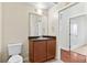 Well-lit bathroom with a wood vanity, a framed mirror, and a toilet at 4100 Albion St # 614, Denver, CO 80216