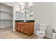 Bathroom with a vanity, toilet, and a view into a walk-in closet with shelving at 4100 Albion St # 614, Denver, CO 80216