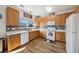 Bright kitchen featuring wood cabinets, white appliances, and wood floors, offering a functional cooking space at 14828 E 118Th Pl, Commerce City, CO 80603