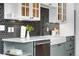 Kitchen featuring white countertops, a farmhouse sink, black tiled backsplash, and glass door cabinets at 624 E 18Th Ave # 4, Denver, CO 80203