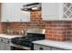 Modern kitchen features white cabinetry, quartz countertops, and a black gas range with a brick backsplash at 624 E 18Th Ave # 4, Denver, CO 80203