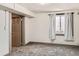 Neutral bedroom with carpet flooring, a window with curtains, and a gray door at 1418 Glencoe St, Denver, CO 80220