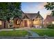 Charming brick home featuring a well-manicured lawn, beautiful landscaping, and a cozy front porch with outdoor seating at 1418 Glencoe St, Denver, CO 80220