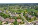 Aerial view of a neighborhood with lush green trees and rolling hills in the background at 1583 Sunset Ridge Rd, Highlands Ranch, CO 80126