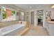 Bright bathroom features a soaking tub, glass shower and neutral tiling at 1583 Sunset Ridge Rd, Highlands Ranch, CO 80126