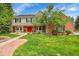 Charming two-story home boasts a beautiful front yard, brick accents, and a welcoming red front door at 1583 Sunset Ridge Rd, Highlands Ranch, CO 80126