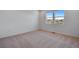 A bright bedroom with carpet and a view from a window, showing nearby homes at 16777 W 94Th Way, Arvada, CO 80007
