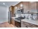The updated kitchen features stainless steel appliances, including a range and refrigerator, and custom wood cabinets at 16777 W 94Th Way, Arvada, CO 80007