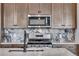 This kitchen features a stainless steel microwave and range and a white marble tile backsplash at 16777 W 94Th Way, Arvada, CO 80007