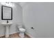 This powder room features a pedestal sink, toilet, framed mirror, and modern black hardware at 16777 W 94Th Way, Arvada, CO 80007